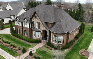 Aerial view of a large brick home with a professionally installed asphalt shingle roof in a residential Middle Tennessee neighborhood