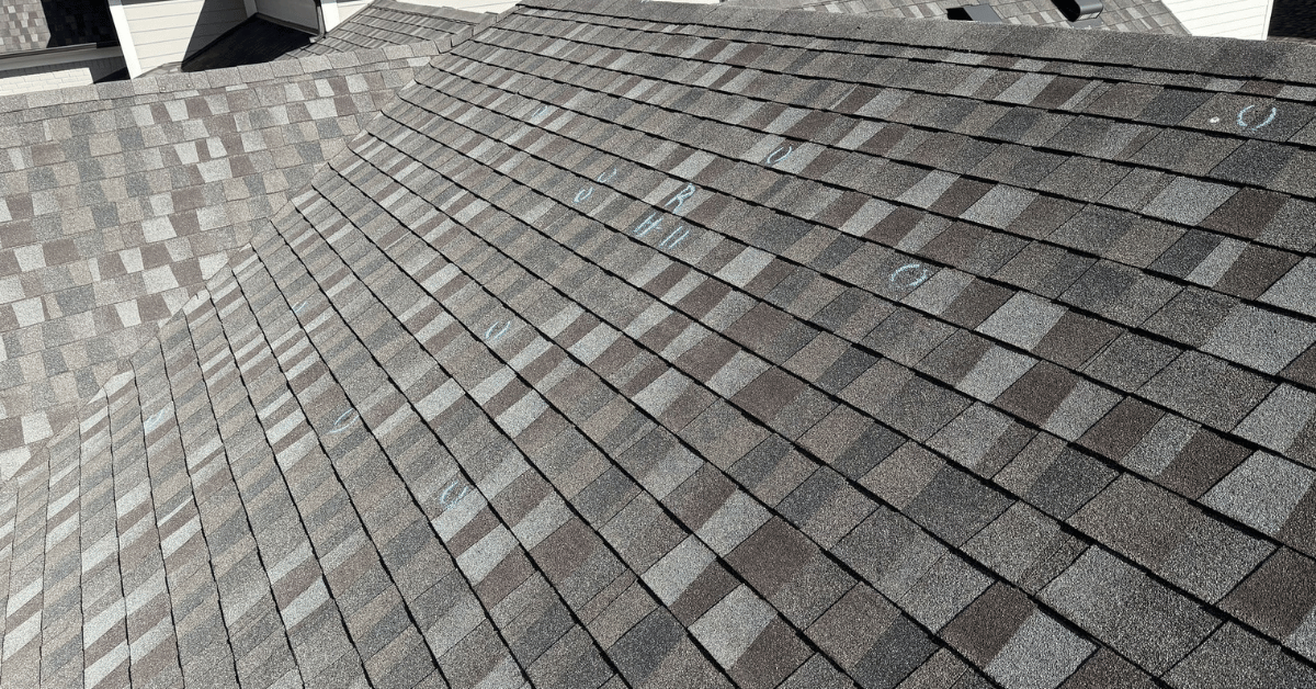 Asphalt shingles marked during a storm damage roof inspection process, identifying hail damage for an insurance claim and potential roof replacement.