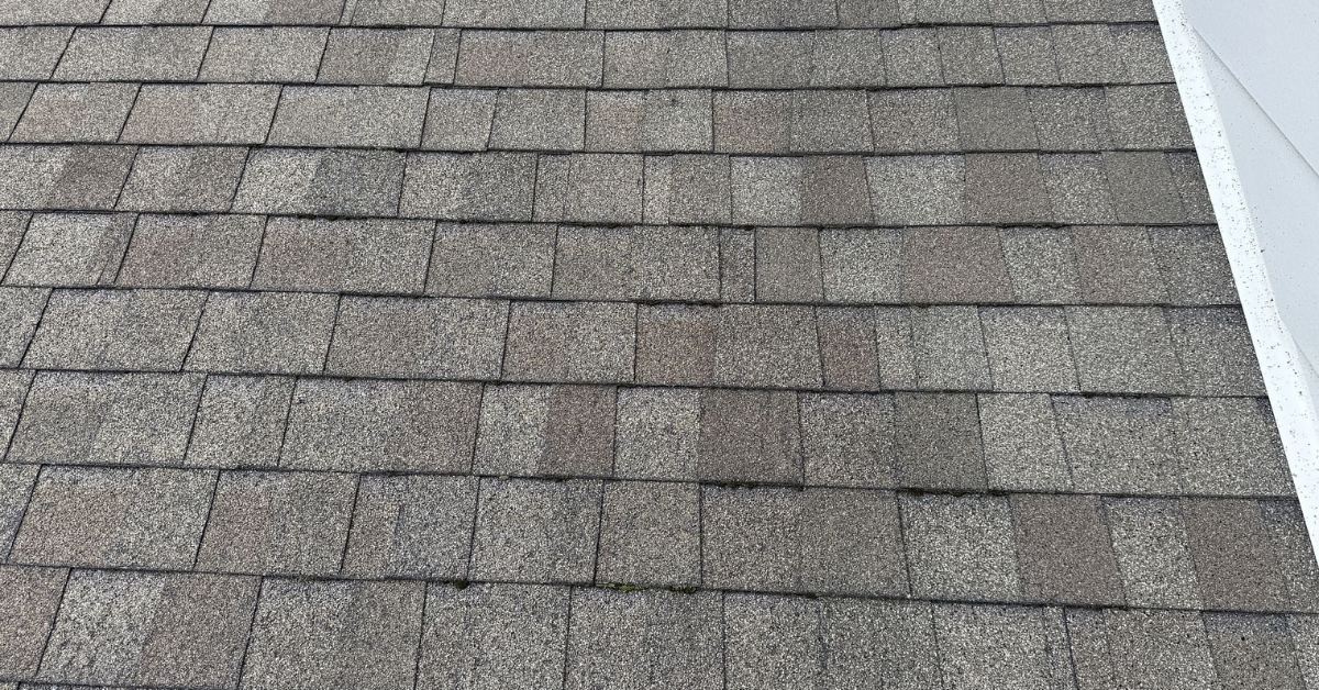 Roof shingles showing patchy discoloration due to granule loss and UV damage from the summer sun.