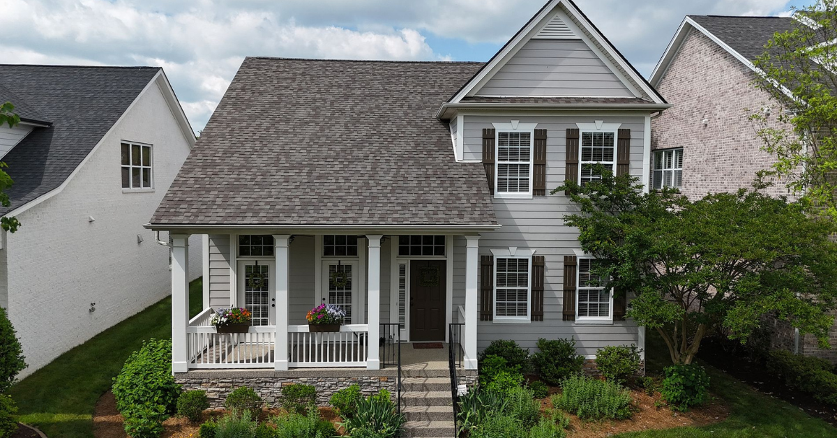 Front view of a two-story house in Franklin, TN showcasing a healthy asphalt shingle roof under clear summer skies.