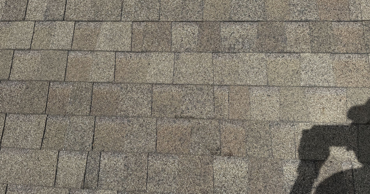Roof surface showing uneven color from sun fading, a common summer roofing issue.