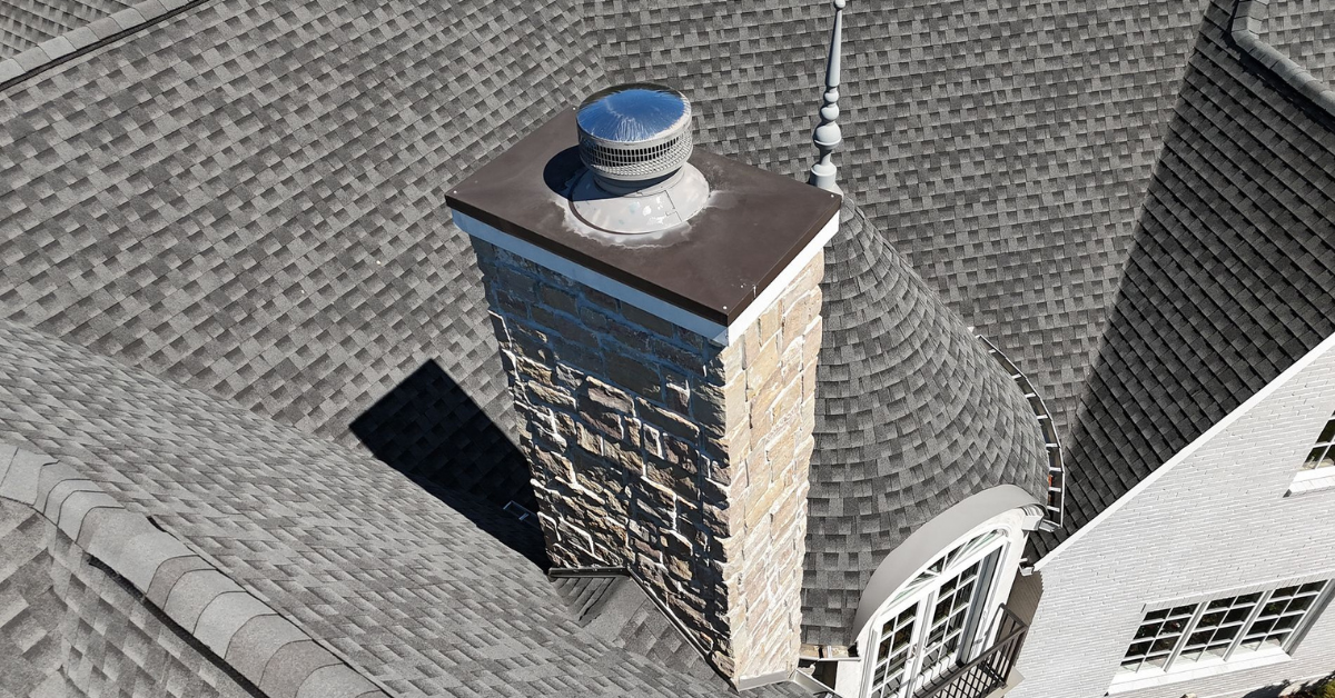 Overhead view of a home's roof showing architectural shingles, skylights, and a chimney—key areas vulnerable to hail damage.