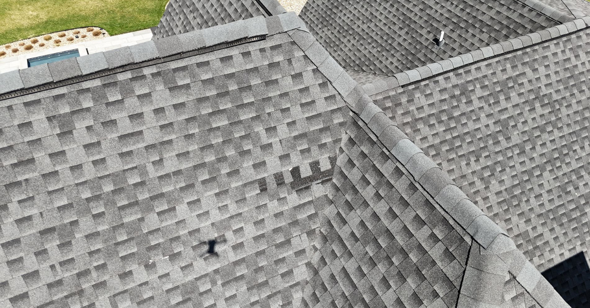 Overhead drone image revealing missing shingles on a steep residential roof, typical after severe hail storms.
