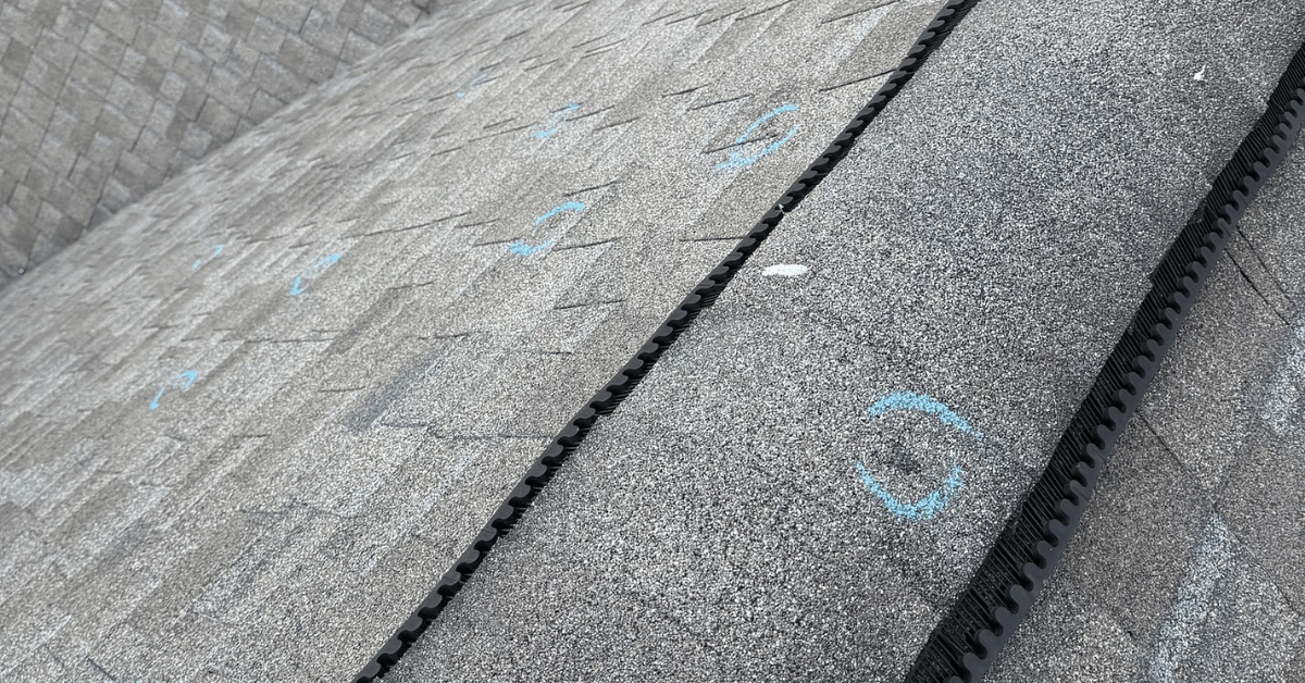 Roof ridge with blue chalk circles indicating hail damage during a home insurance roof inspection.