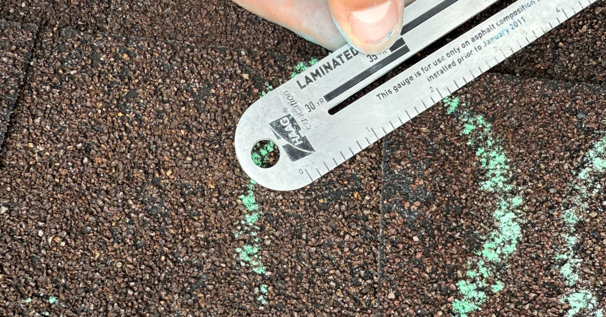 HAAG-certified roof inspector using a gauge to assess the size and severity of hail damage on shingles.