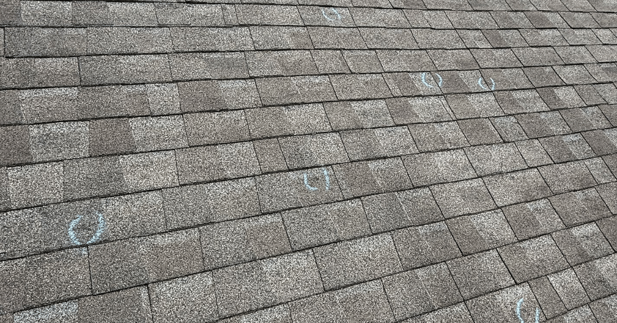 Shingles marked in blue chalk to indicate hail impact, a common cause for roof insurance claims in Middle Tennessee.