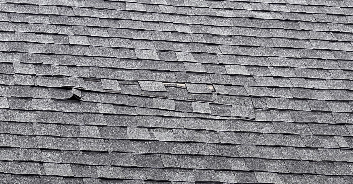 Visible damage from high winds with lifted and missing shingles on an asphalt roof in Middle Tennessee
