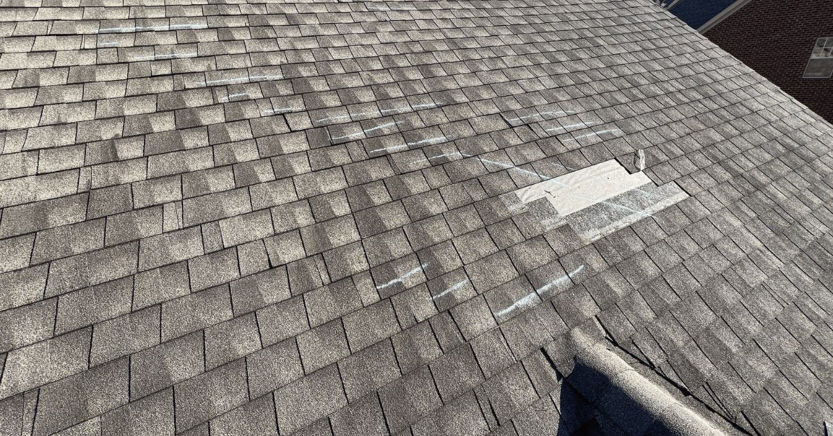Roof section showing multiple chalk-marked shingles indicating wind lift and shingle displacement.