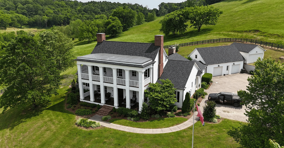 Aerial view of a historic white home in College Grove with a new black CertainTeed Landmark Pro roof and manicured landscaping.