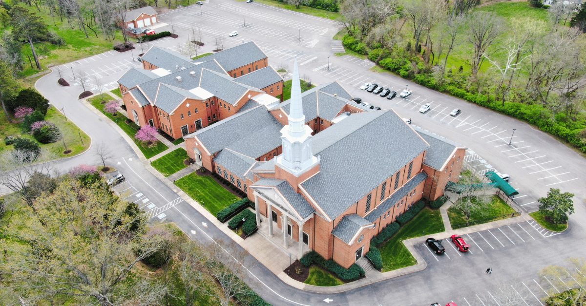 Aerial shot highlighting the front steeple and completed roofing system at Hillsboro Church of Christ.