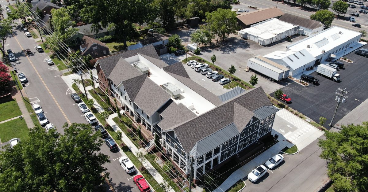 Drone shot showing full roofing system with architectural shingles and metal accents on new office complex.
