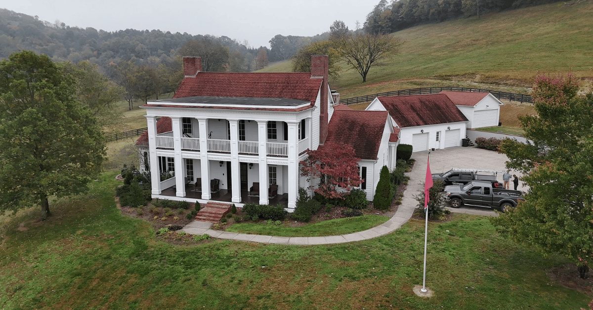 Front view of the same home before roof replacement, featuring faded red shingles with visible wear and storm damage.