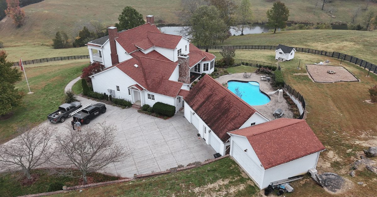 Aerial rear shot of the home showing weathered red shingles and property layout including a pool and detached garage.
