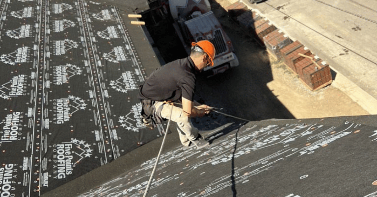 Roofer Installing Underlayment with Safety Harness