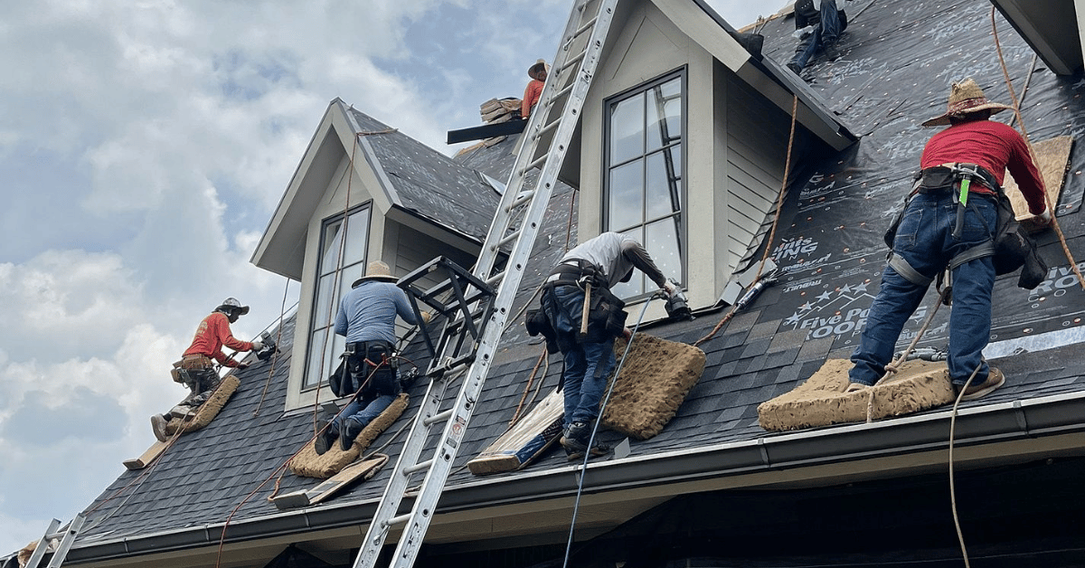 Skilled Roofers Installing a New Roofing System Five Points Roofing team members professionally installing shingles on a steep roof, emphasizing proper technique and safety.