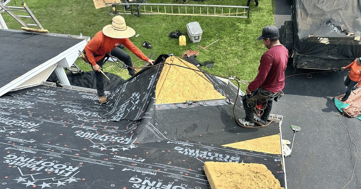 Roofing crew laying underlayment in a roof valley during early stages of a roof replacement project in Middle Tennessee.