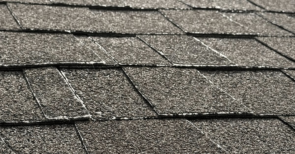 Asphalt roof shingles showing visible warping and lifting edges due to prolonged exposure to intense heat and UV rays.