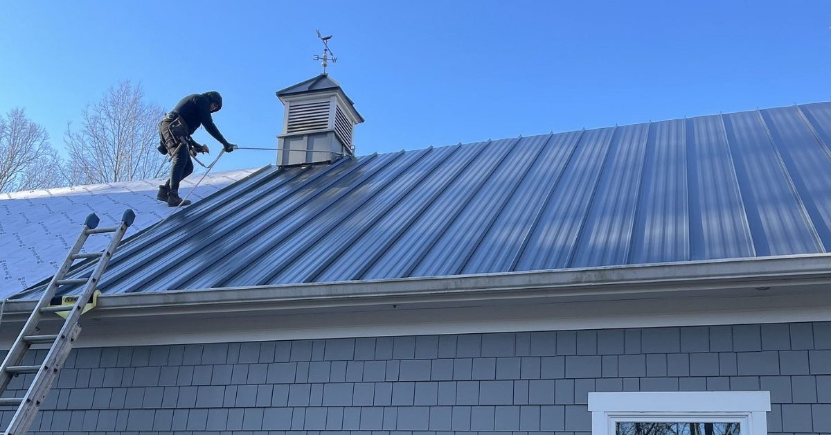 Roofing technician installing standing seam metal panels on a steep slope, ensuring safety, quality, and durability on a Franklin, TN home.