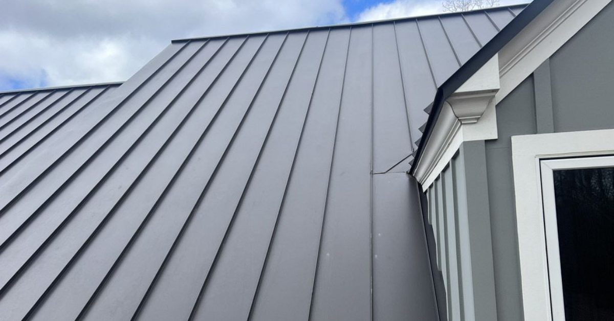 Detailed view of storm-impacted standing seam metal roofing around a dormer window, showing minor dents prior to the full roof replacement in Franklin, Tennessee.