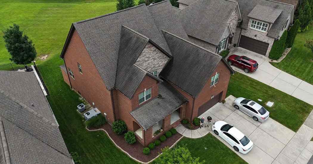 Overhead view of a Brentwood, TN home with aging shingles and visible roof stains, a common cause for full roof replacement delays.