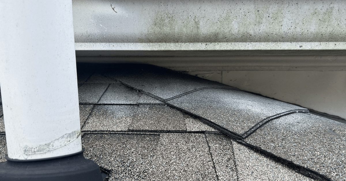 Close-up of misaligned asphalt shingles near the gutter with visible gaps.