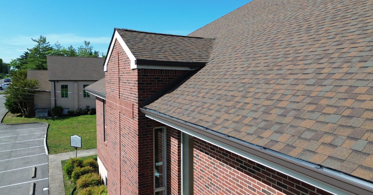 New Architectural Shingles on a Church — Franklin, TN Close-up drone view of new brown architectural asphalt shingles and gutters on a brick church building in Franklin, Tennessee