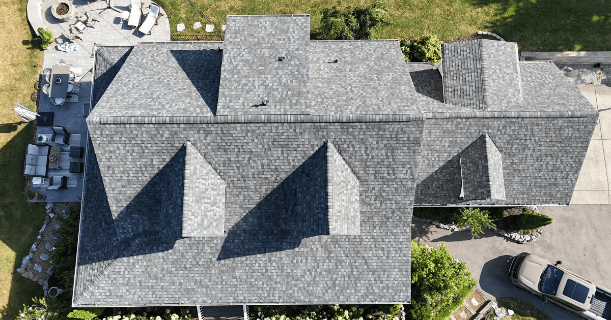 Aerial view of a completed charcoal gray asphalt shingle roof with dormers and a wraparound porch in Franklin, TN